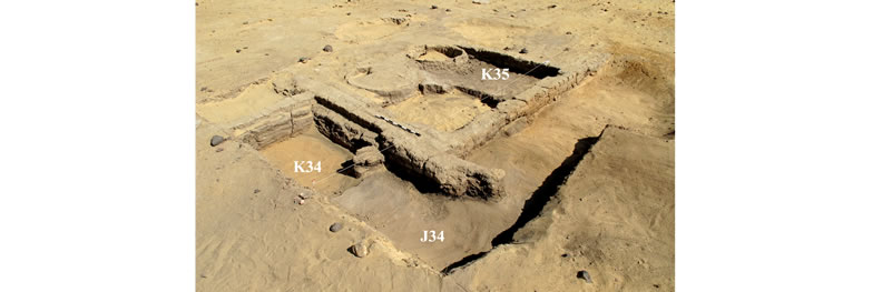 Figure 5 View (looking northwest) of Structure A, the 4m x 4m squares are labeled in their southeast corners. Inside Room I, the clean sand that underlies Level 3 is visible in Square K34 (and the western portion of J34), while the top of Level 3 (the ash and debris that accumulated prior to the construction of Structure A) is visible in Square K35 (and the western portion of J34).